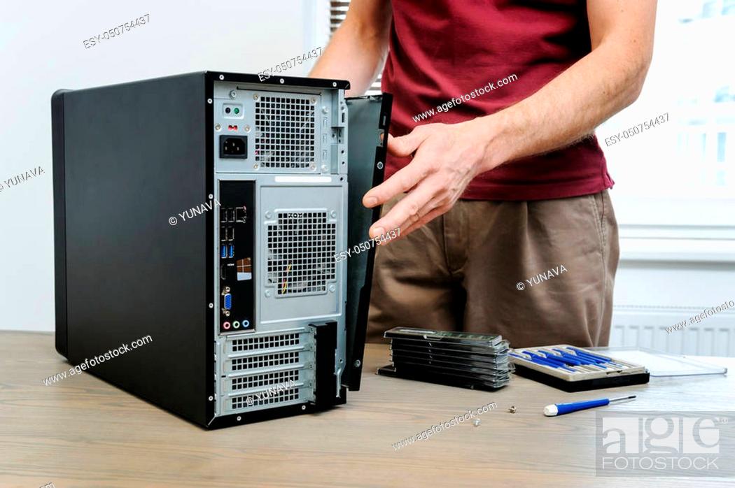 Stock Photo: A man is removing the side panel from the computer for access inside.
