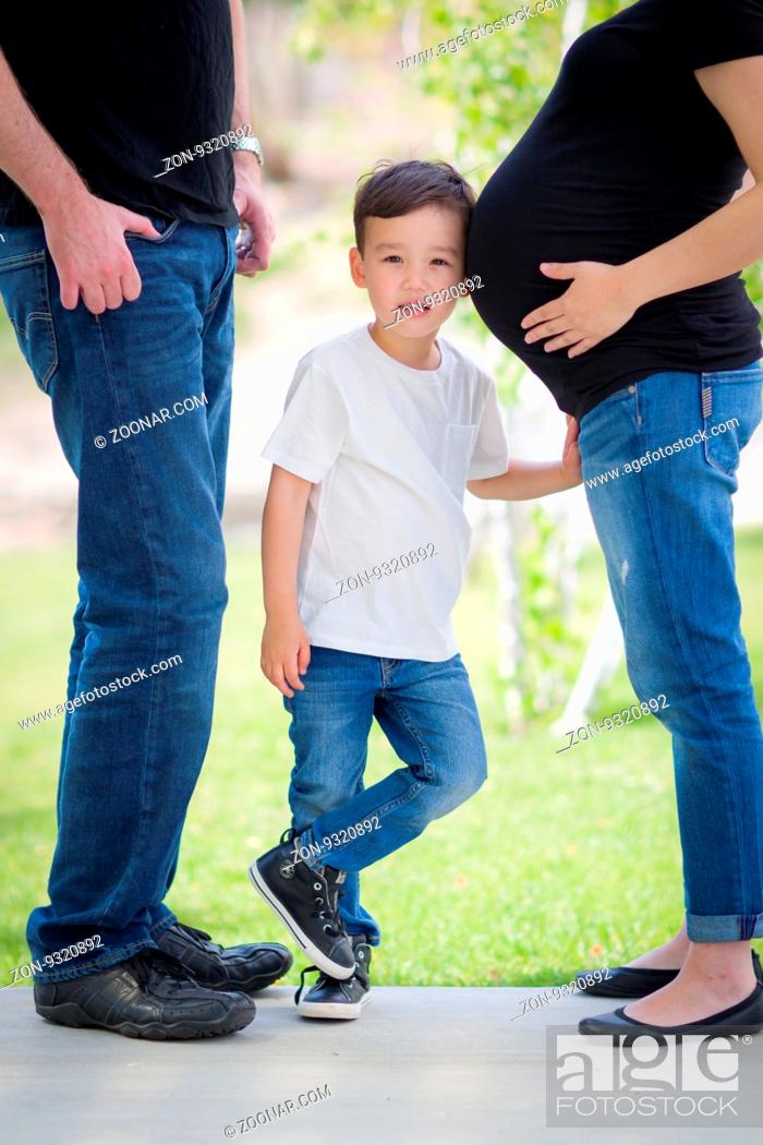 Stock Photo: Courious Young Mixed Race Son With Ear on Pregnant Belly of Mommy with Daddy Nearby.