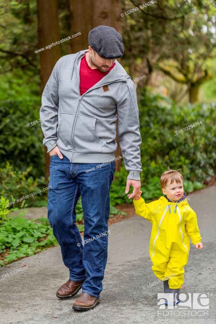 Stock Photo: Father holding hands with young daughter while taking a walk in the park; North Vancouver, British Columbia, Canada.
