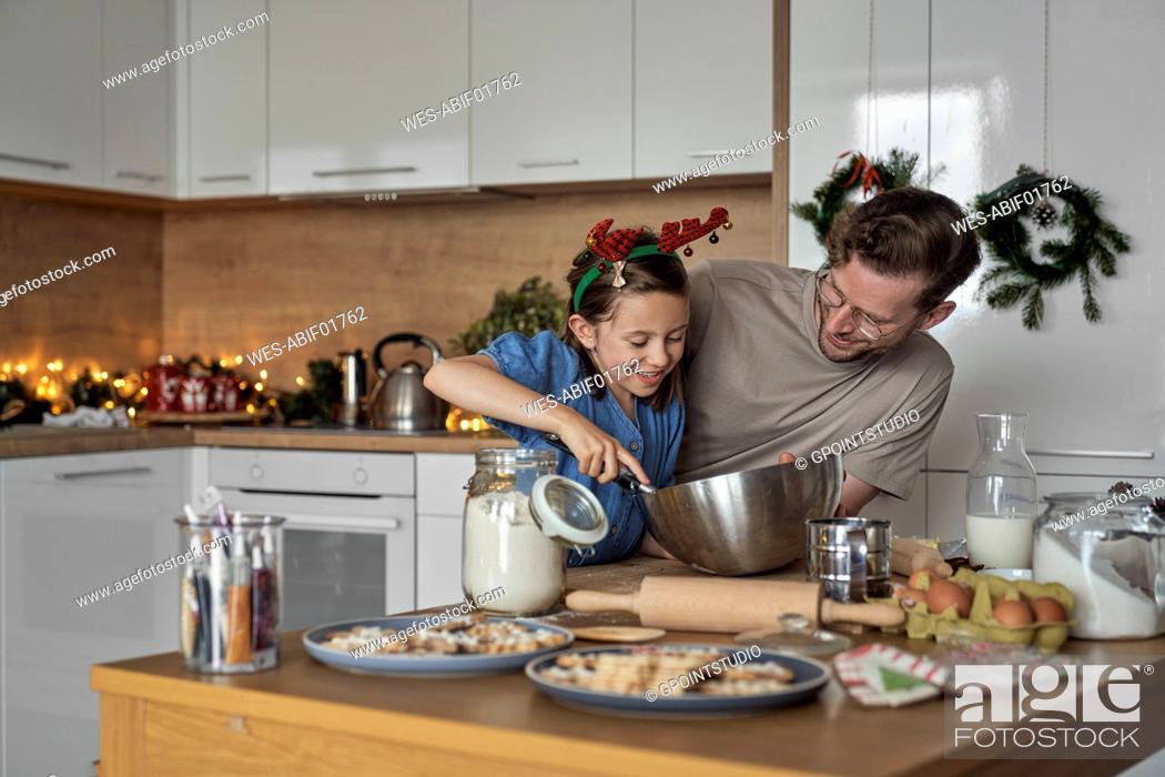 Stock Photo: Happy girl mixing cookie dough standing by father in kitchen.
