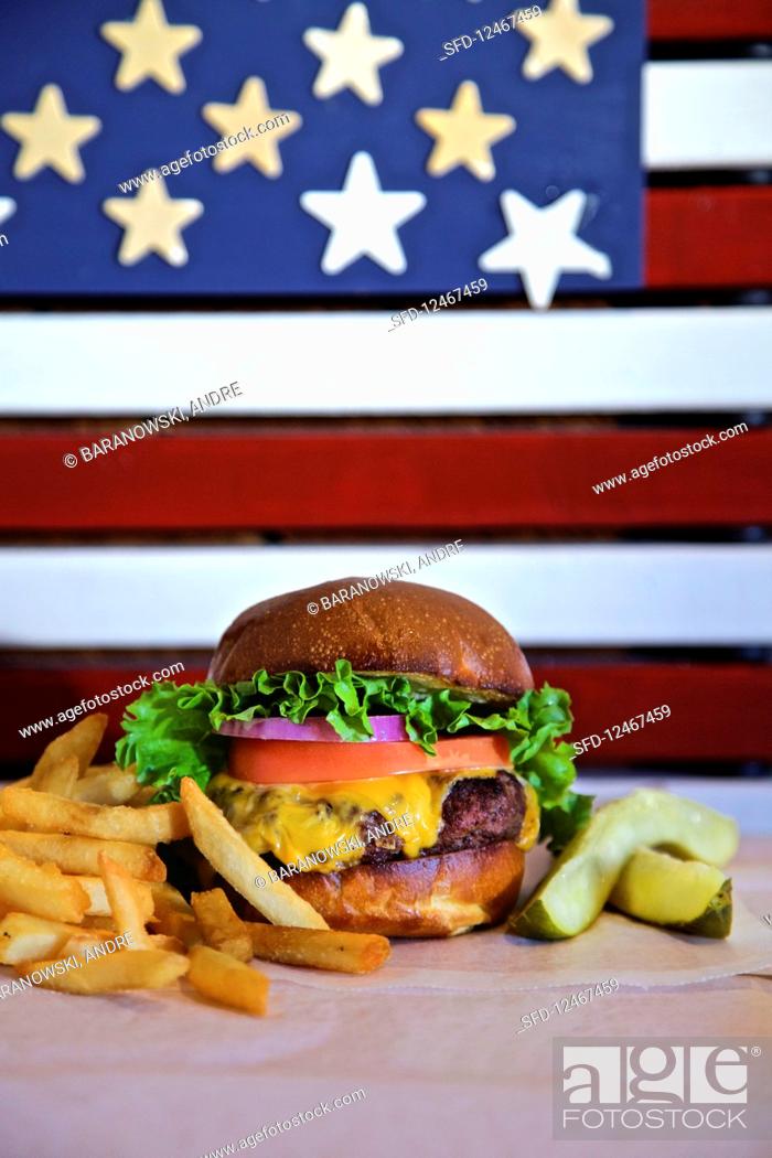 Stock Photo: Cheese burger with lettuce tomato, onion, pickle and french fries with american flag.