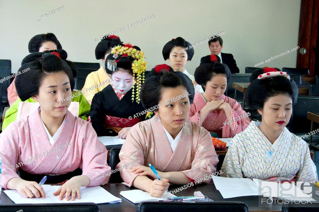 Stock Photo: Geisha and Maiko apprentice Geisha attending a class at 'Mia Garatso' school of Geisha while there are three young women wearing plain kimono seated at desk in.