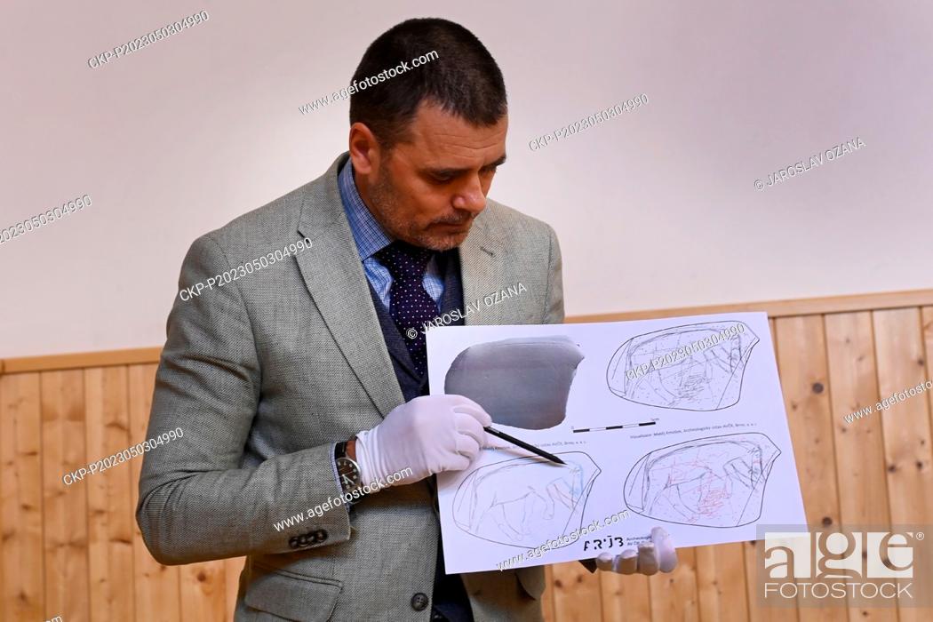 Stock Photo: Experts from the Moravian Museum in Brno present a unique object from the older Stone Age, a river stone with engravings of a mammoth and a horse's head.
