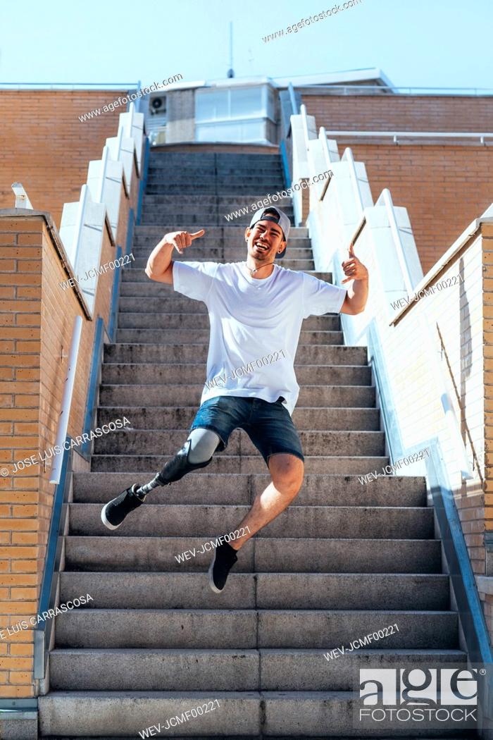 Stock Photo: Happy young man with leg prosthesis jumping on stairs inb the city.