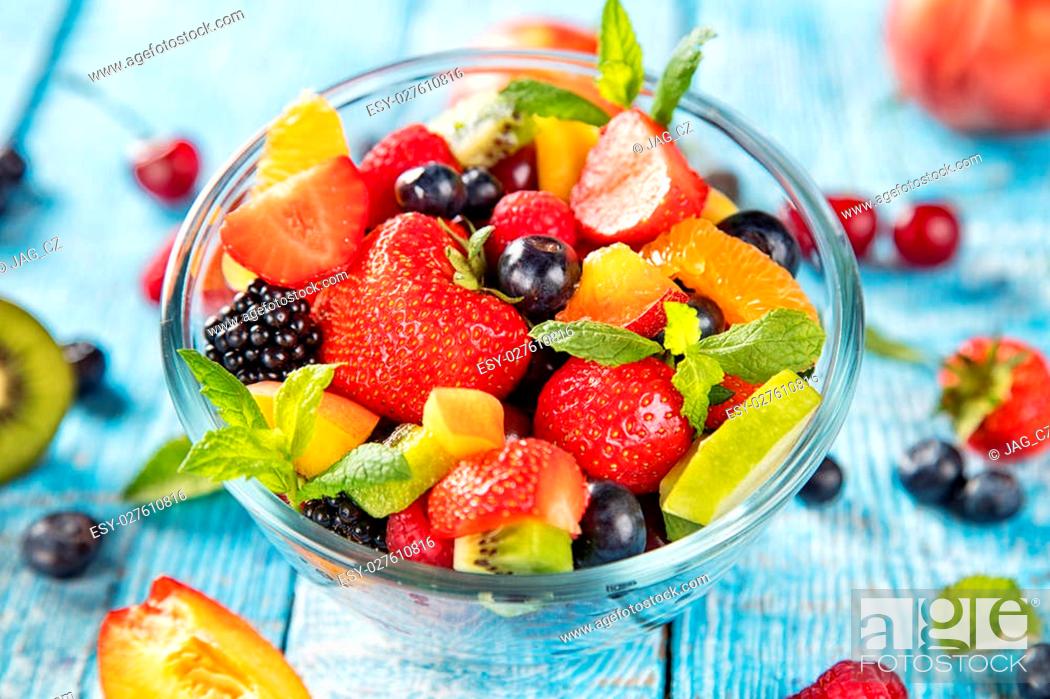 Stock Photo: Fresh fruit salad with various kind of berry and citrus fruit served in glass bowl, placed on wooden table.