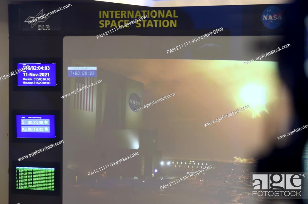 Stock Photo: 11 November 2021, Bavaria, Oberpfaffenhofen: The flames of a SpaceX Falcon 9 rocket can be seen on a large video screen in the Columbus Control Center at the.