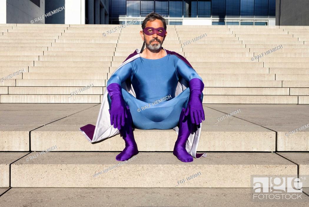 Stock Photo: Portrait of man dressed as superhero sitting on steps.