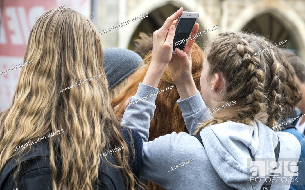 Stock Photo: Germany, Munich. Marienplatz. Young, blonde haired girls watch the glockenspiel in the town square.