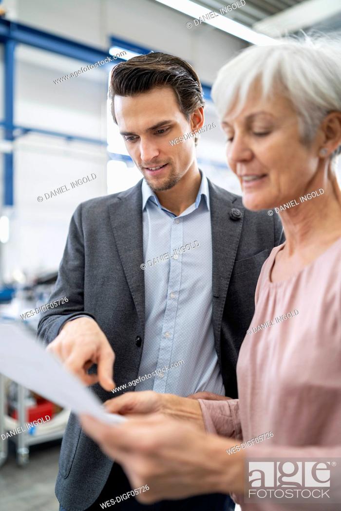 Stock Photo: Businessman and senior woman looking at plan in a factory.