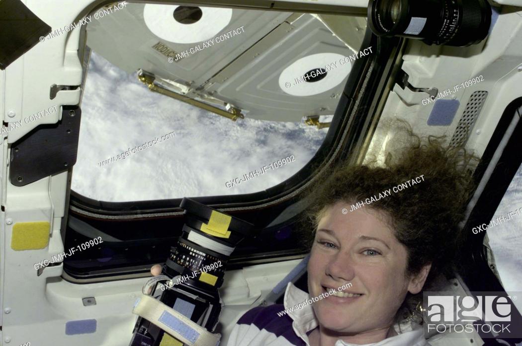 Stock Photo: Astronaut Susan J. Helms, STS-101 mission specialist, prepares to take still photos through overhead windows on the aft flight deck of the Space Shuttle.