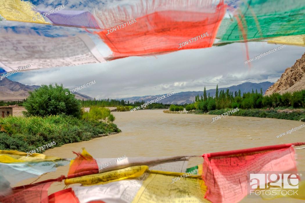 Stock Photo: Mid-summer view of the Indus River from the Buddhist prayer flags decorated bridge in Central Ladakh. As the river is fed by glaciers and snow.