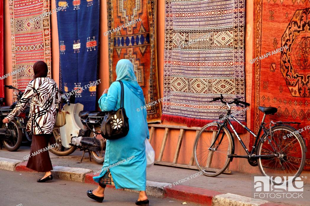 Veiled Women Walking Past Berber Rugs, The Rug Market