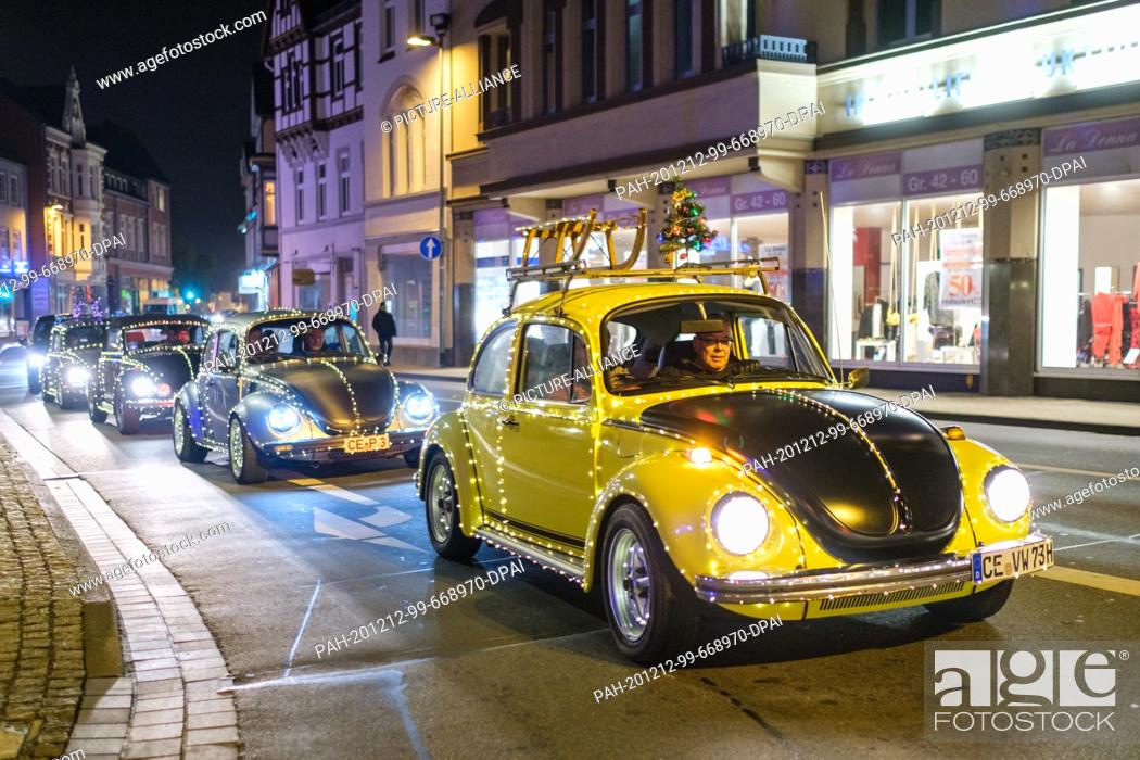 Stock Photo: 12 December 2020, Lower Saxony, Celle: Shining Volkswagen Beetles drive through the city centre of Celle. Since the Christmas markets have been cancelled.