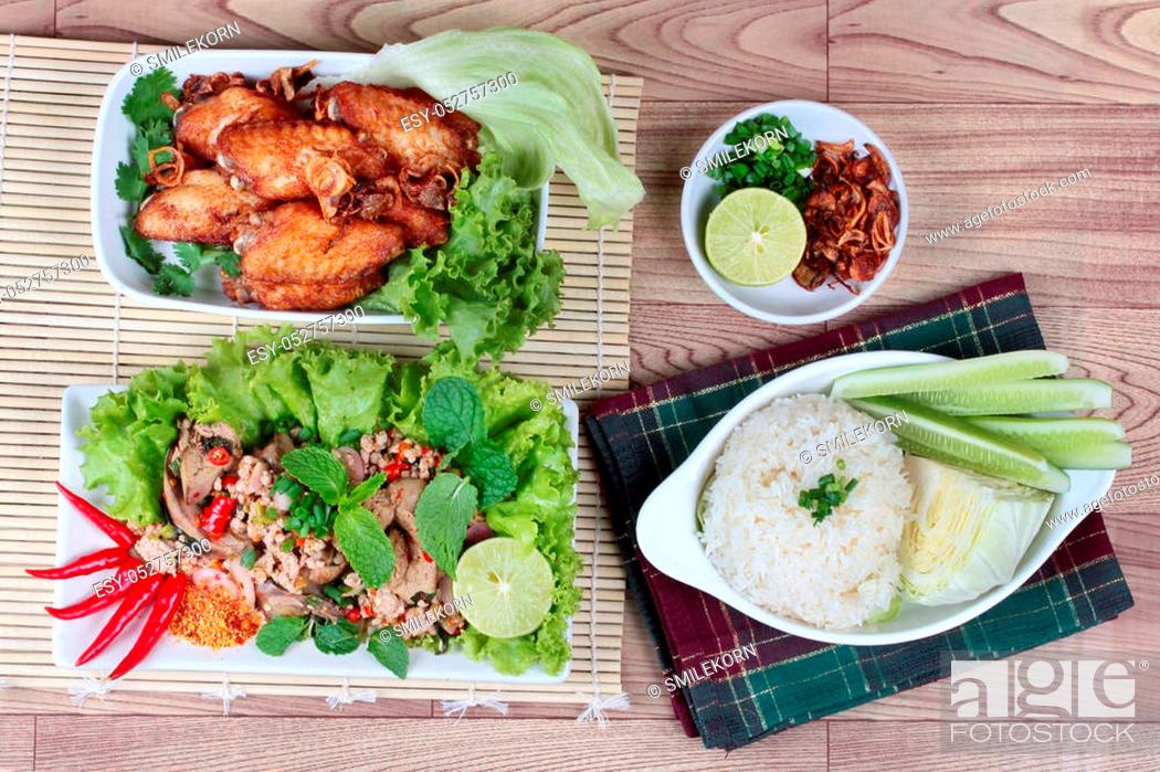 Stock Photo: A dish of sticky rice with cucumber and cabbage served side dish as a disk of fried chicken topped fried sliced red onion and spicy sour chicken salad are.