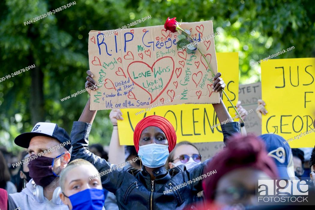 Stock Photo: 30 May 2020, Berlin: A participant in a rally in front of the U.S. Embassy against the violent death of African American George Floyd by a white policeman holds.