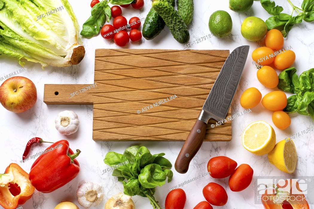 Stock Photo: Fresh vegetables, salad leaves and greens, cutting board with chefs knife.