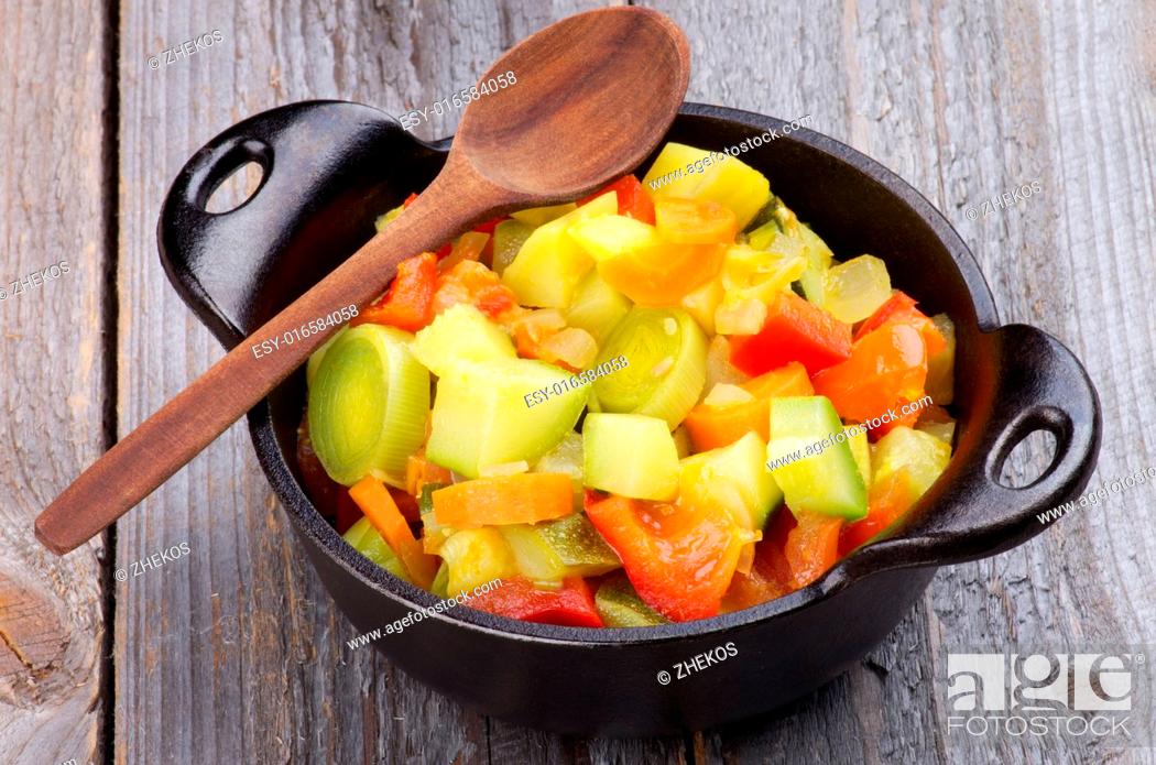 Stock Photo: Vegetable Stew with Zucchini and Leek in Black Saucepan with Wooden Spoon isolated on Rustic background.