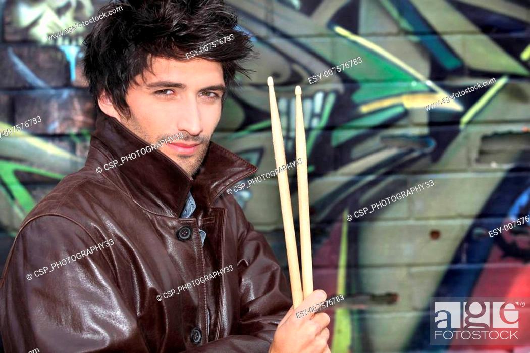 Stock Photo: musician with drumsticks against graffiti wall.