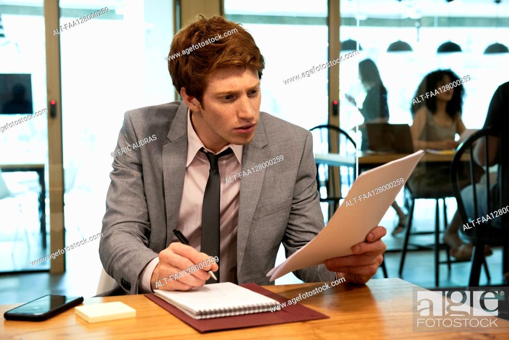 Stock Photo: Young businessman writing on notebook in office.