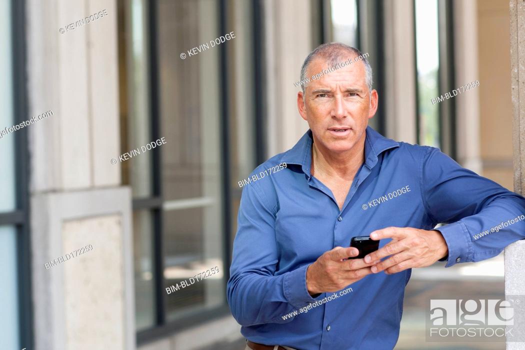 Stock Photo: Caucasian businessman using cell phone in city.