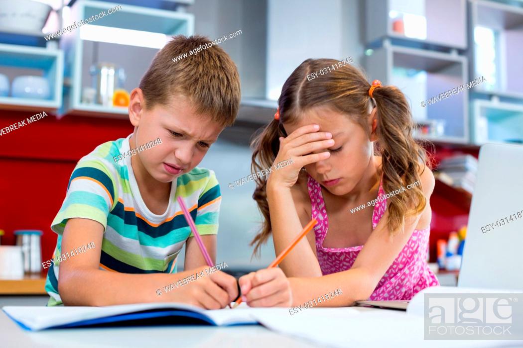 Stock Photo: Tense siblings doing homework in kitchen.