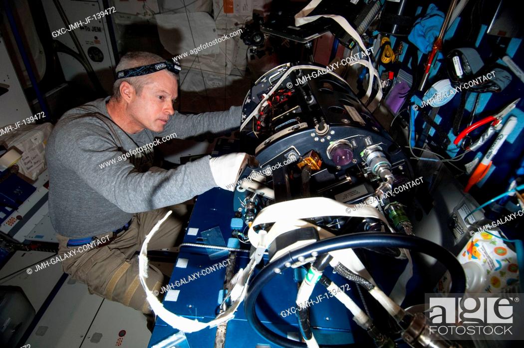 Stock Photo: NASA astronaut Steve Swanson, Expedition 40 commander, works with the Multi-user Drop Combustion Apparatus (MDCA) at a workstation in the Harmony node of the.