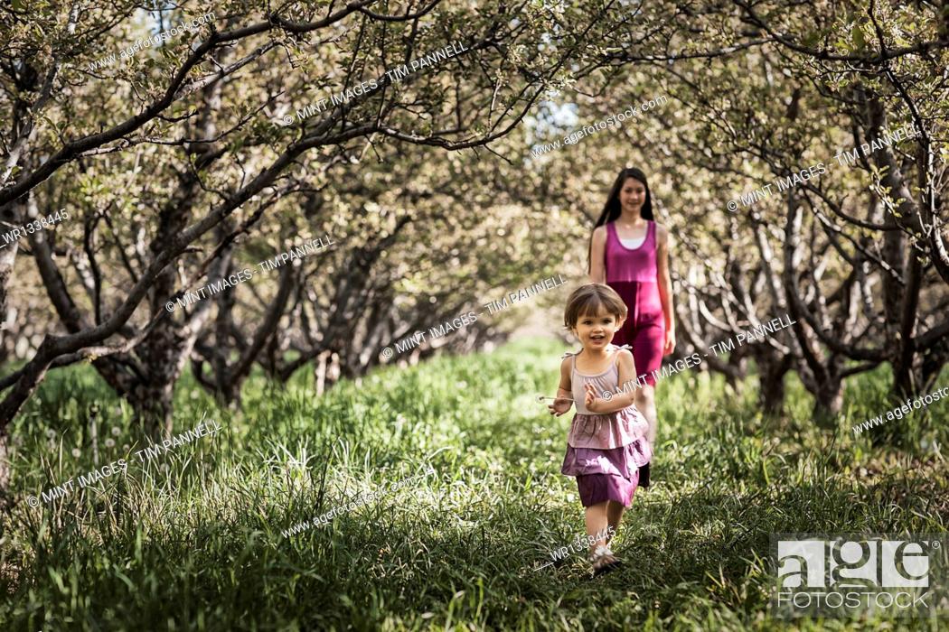 Stock Photo: Two children walking in a woodland tunnel of overarching tree branches.