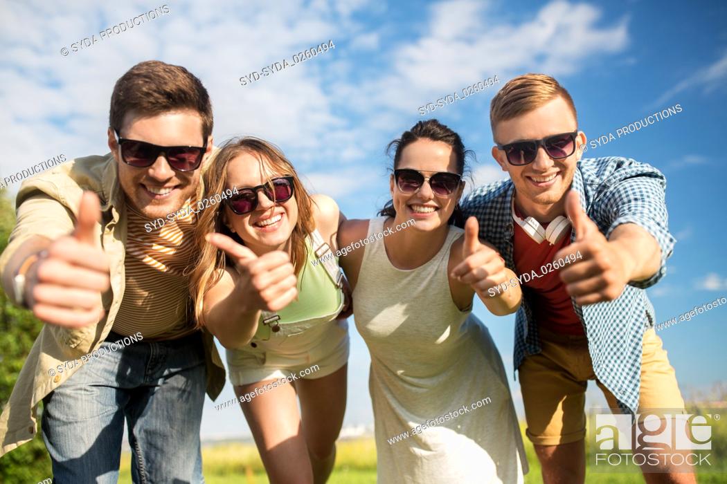 Stock Photo: happy teenage friends showing thumbs up in summer.