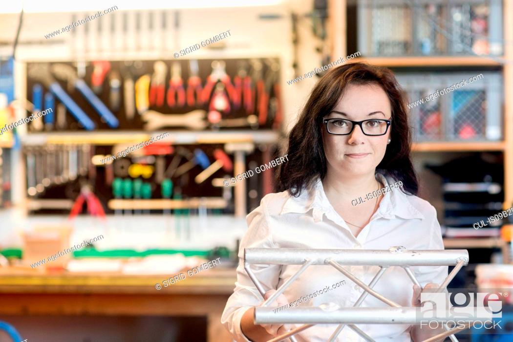 Stock Photo: Woman in bicycle repair shop holding bicycle part.