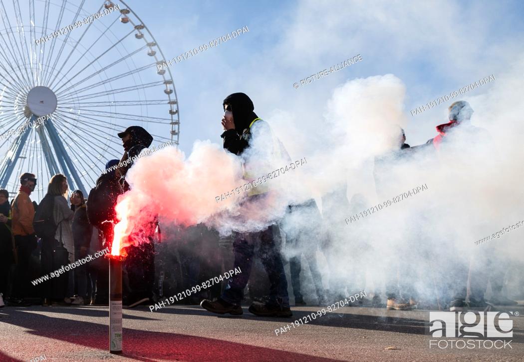 Stock Photo: 10 December 2019, France (France), Lyon: Pyrotechnics burns during a demonstration in the context of strikes and protests against the pension reform in France.