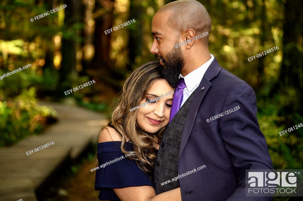 Stock Photo: Full of love photo of an affectionate mixed race young couple holding each other in the woods in the Lynn Canyon Park, North Vancouver, British Columbia, Canada.