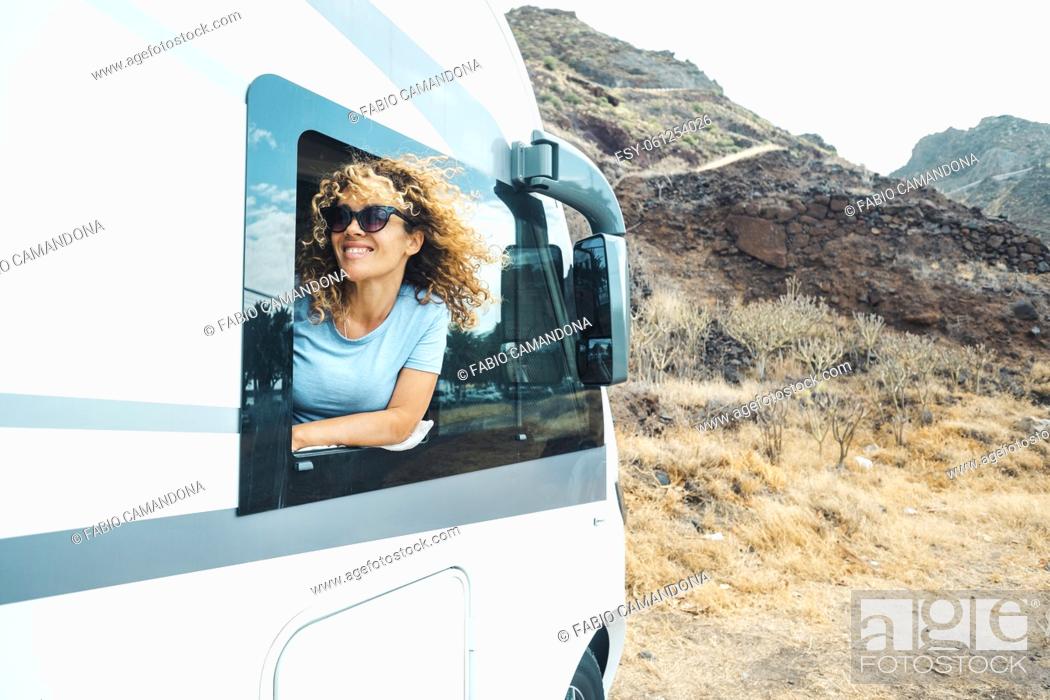 Photo de stock: People and travel holiday vacation destination. Happy young adult woman smile and enjoy nature off road parking outside the window of her modern motor home.