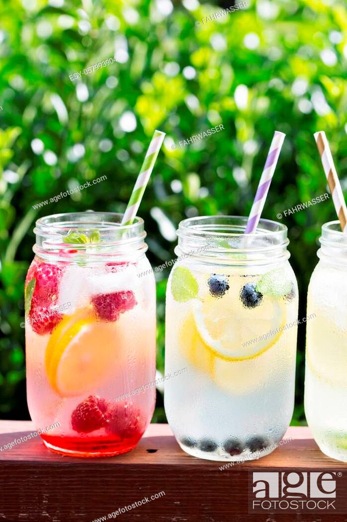 Stock Photo: Variety of lemonade in mason jars with berries and fruits on the front porch.
