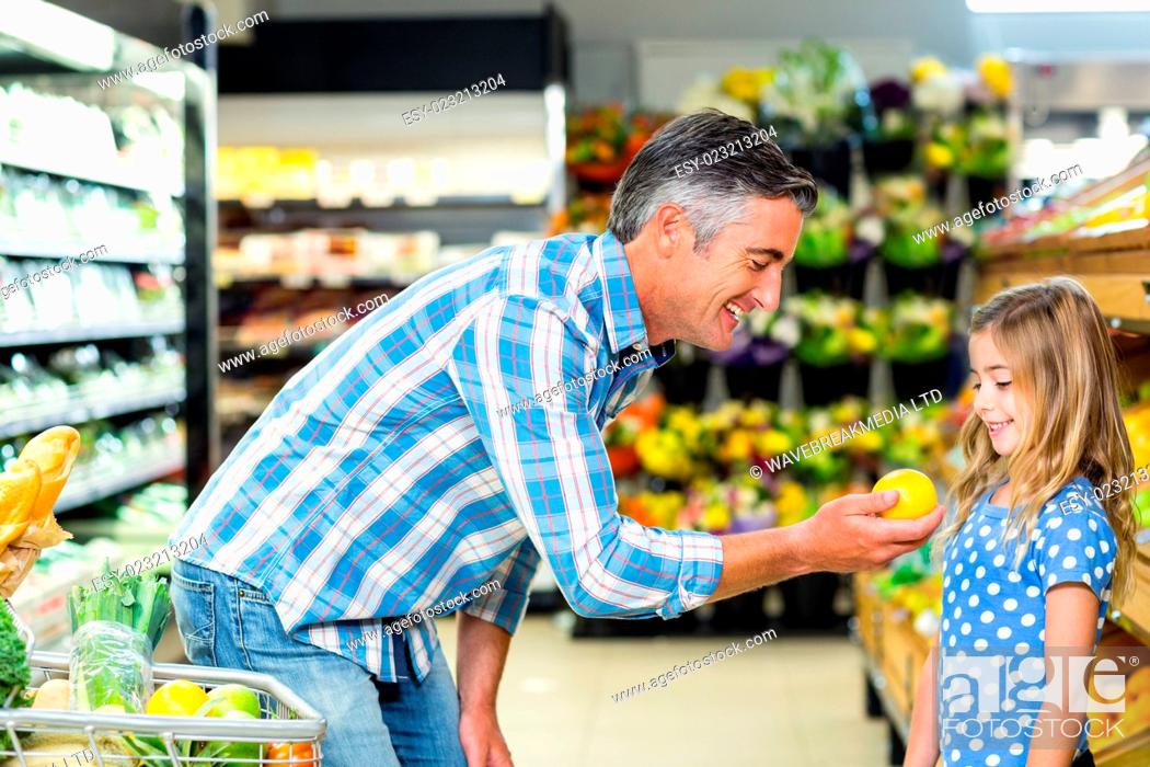 Stock Photo: Smiling father giving an apple to his cute daughter in the supermarket.