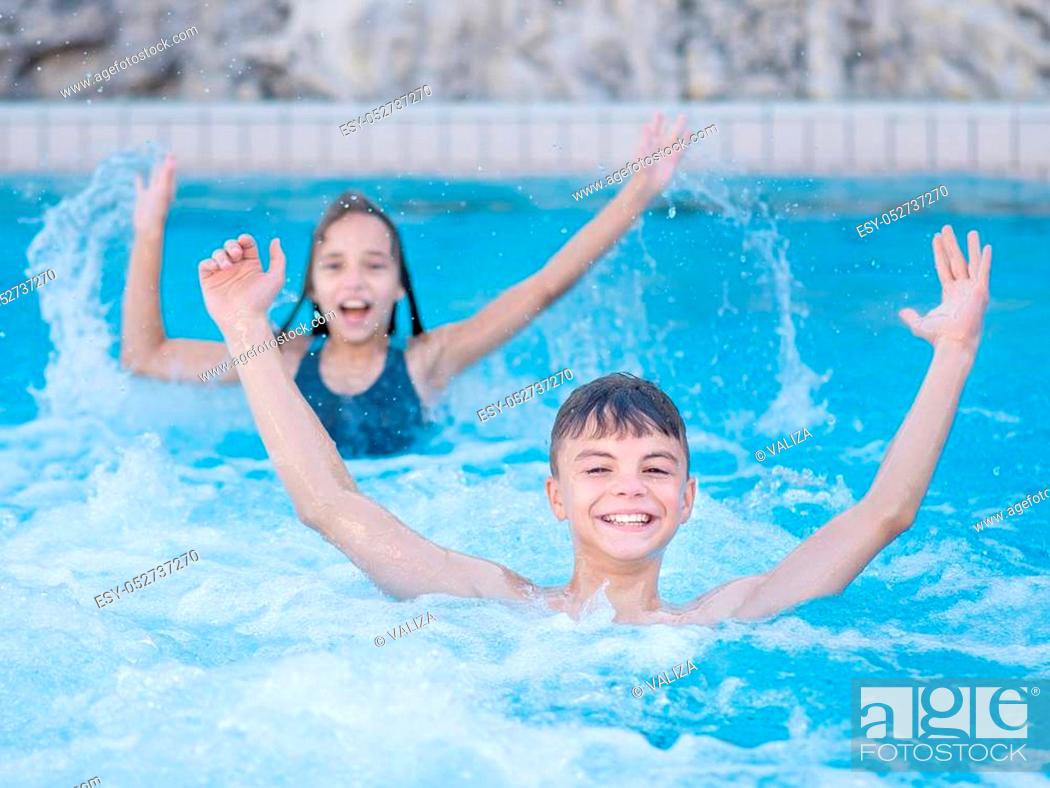 Stock Photo: Smiling beautiful children in the swimming pool at aquapark. Happy teen boy and girl - brother and sister having fun together enjoyable time on vacation.