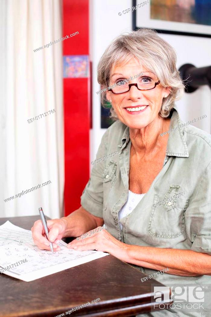 Stock Photo: Senior woman completing a crossword puzzle.