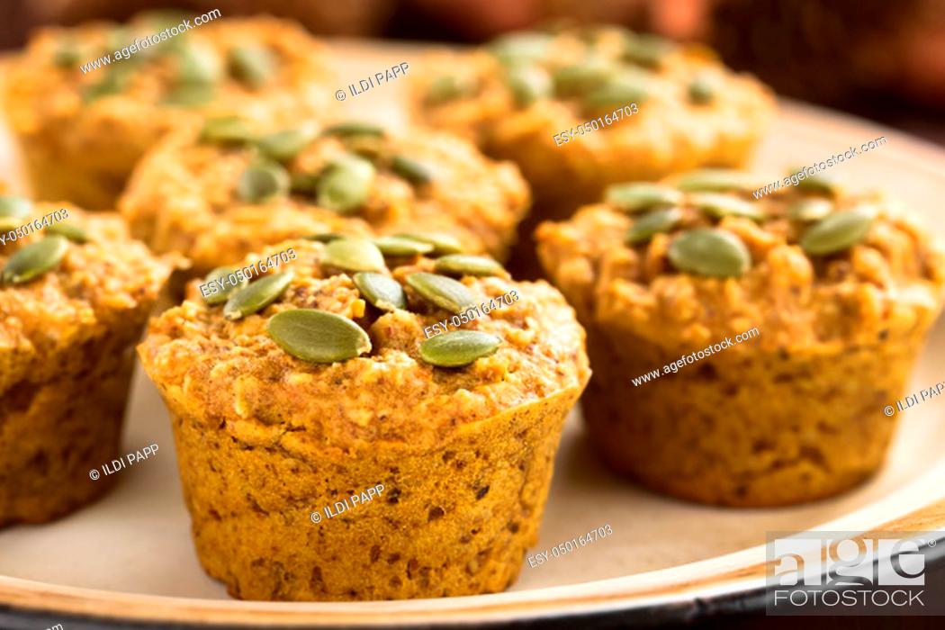 Stock Photo: Fresh homemade pumpkin walnut oatmeal muffin with pepita pumpkin seeds on top (Selective Focus, Focus on the first two seeds on the first muffin).