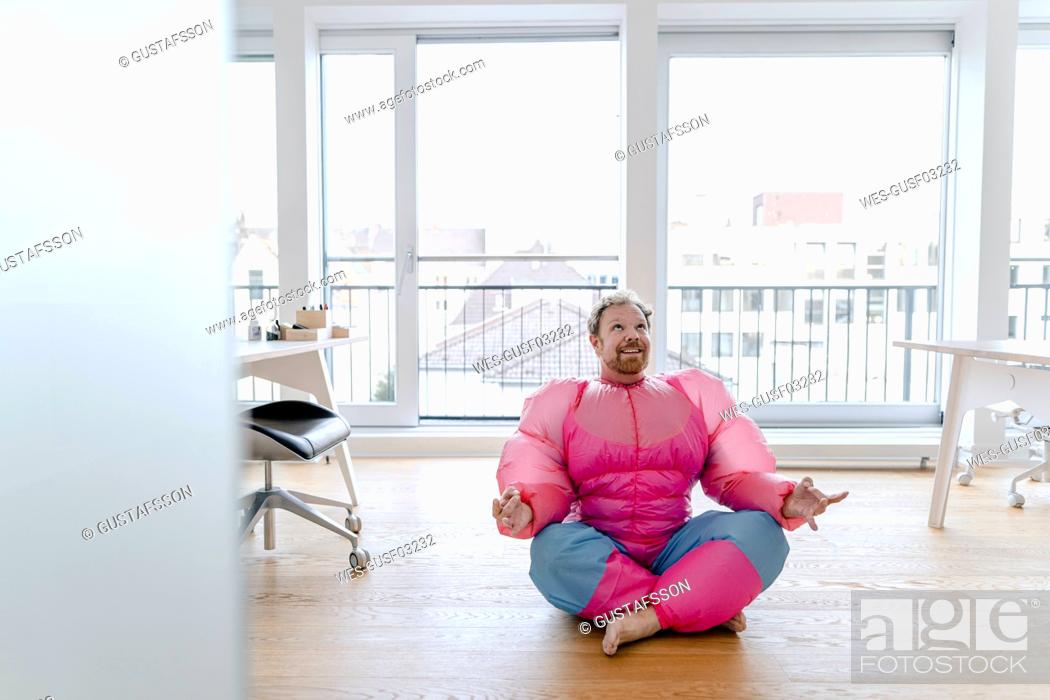 Stock Photo: Businessman in office wearing pink bodybuilder costume practicing yoga.