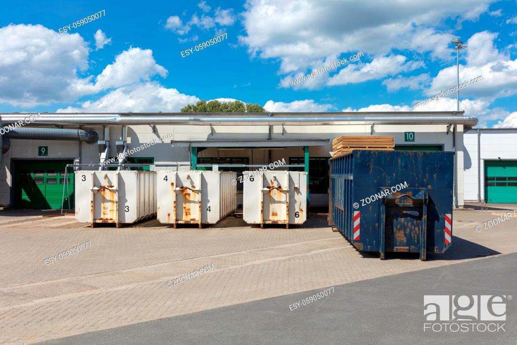 Stock Photo: white garbage containers are standing on a factory site and there are other garbage containers next to them.