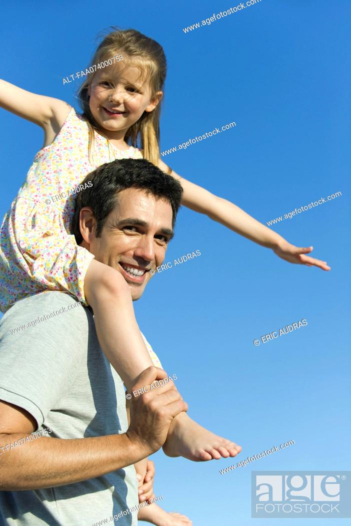 Photo de stock: Father carrying daughter on his shoulders.
