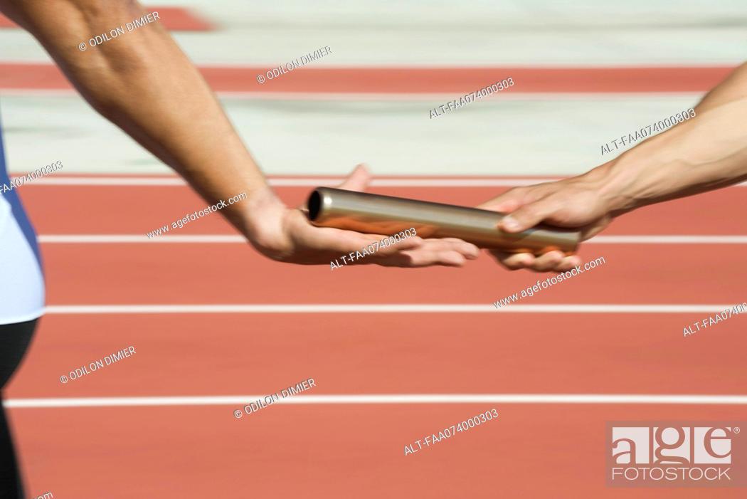 Stock Photo: Runners exchanging baton in relay race, cropped.