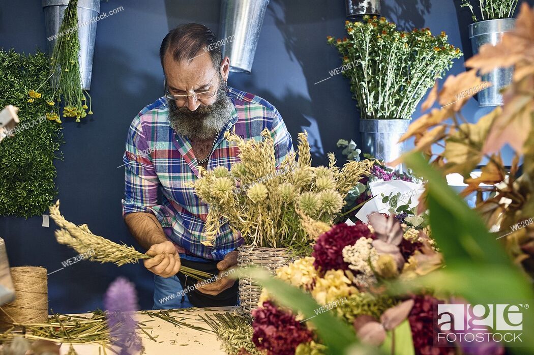 Stock Photo: A florist taking care of various flowers and bouquets in his shop.
