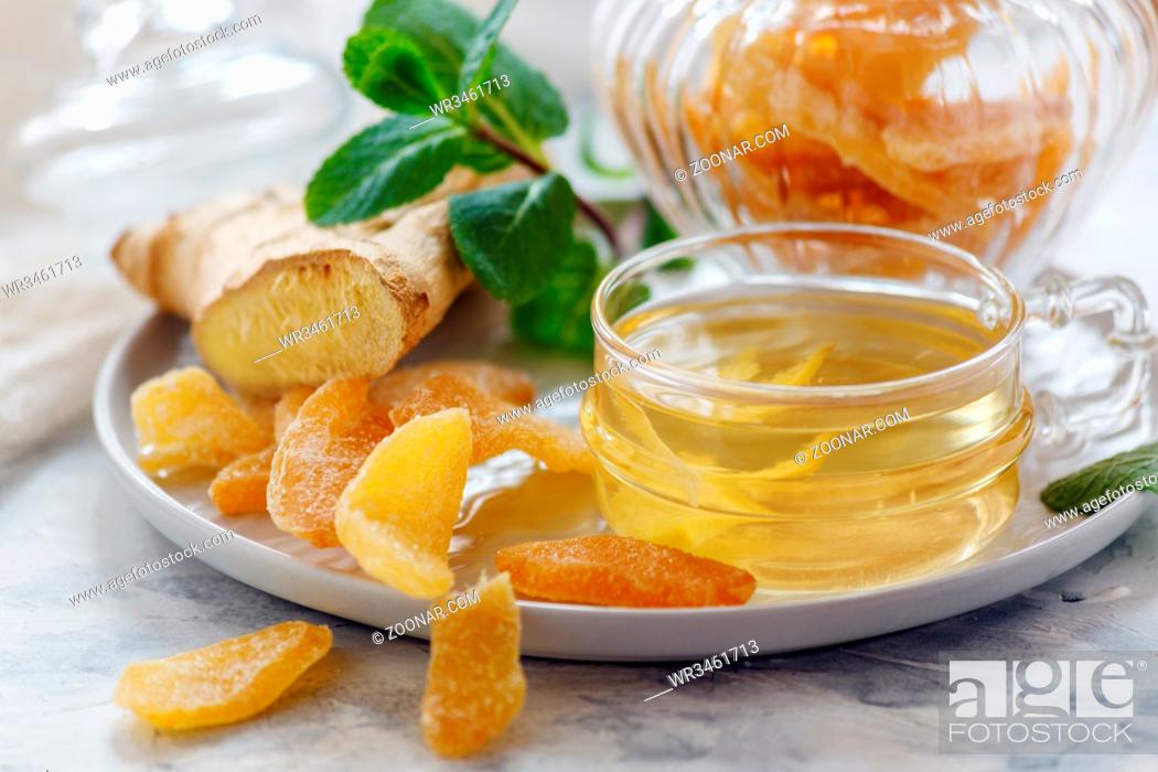 Stock Photo: Dish of ginger tea, ginger root and slices of candied ginger on a white kitchen table selective focus.