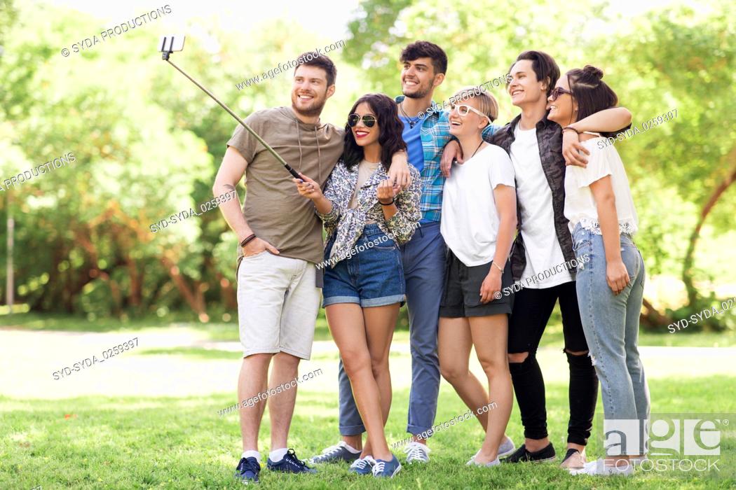 Stock Photo: friends taking picture by selfie stick at summer.