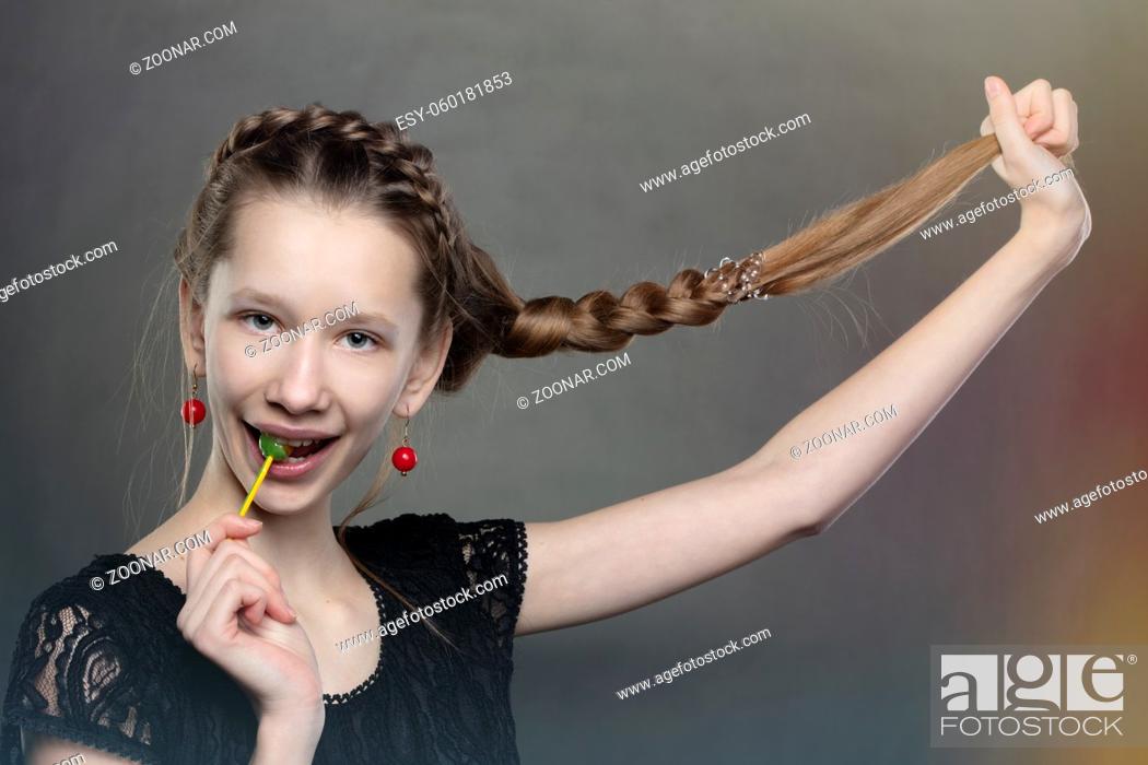 Stock Photo: A funny and mischievous teenager girl with a lollipop and a long braid.
