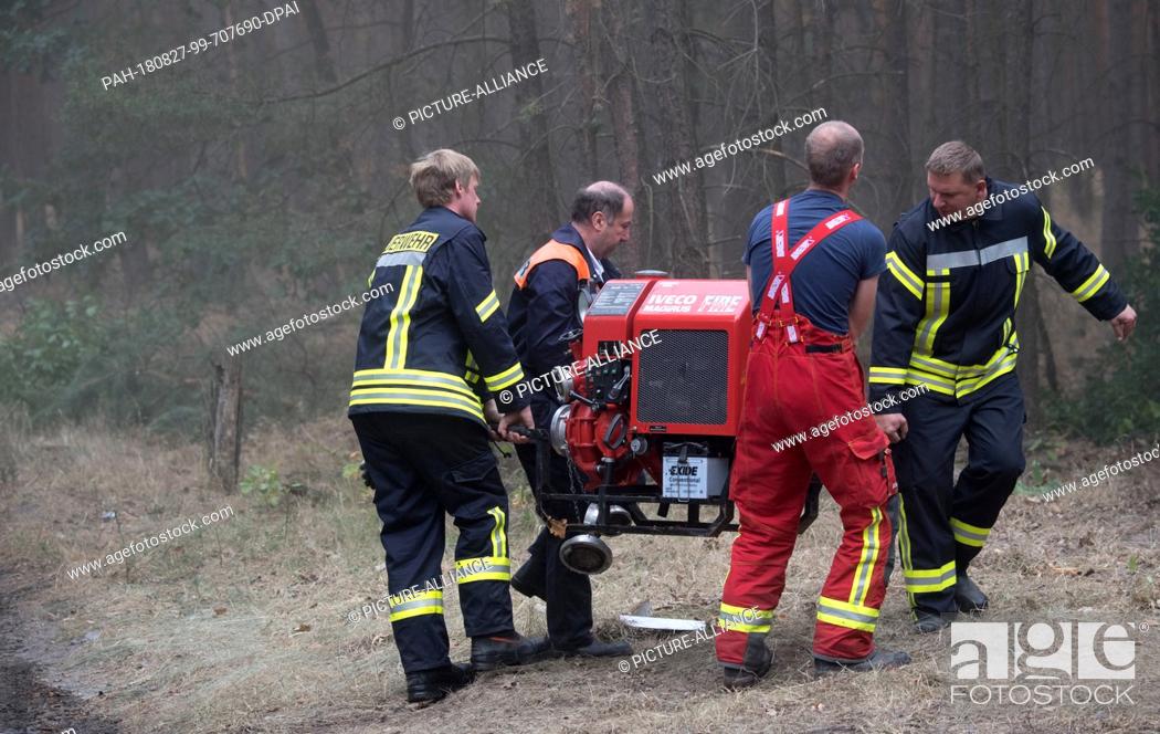 Stock Photo: 27 August 2018, Treuenbrietzen, Germany: Firefighters tow a water pump in a forest near Treuenbrietzen. About 350 firefighters are still on duty to fight forest.