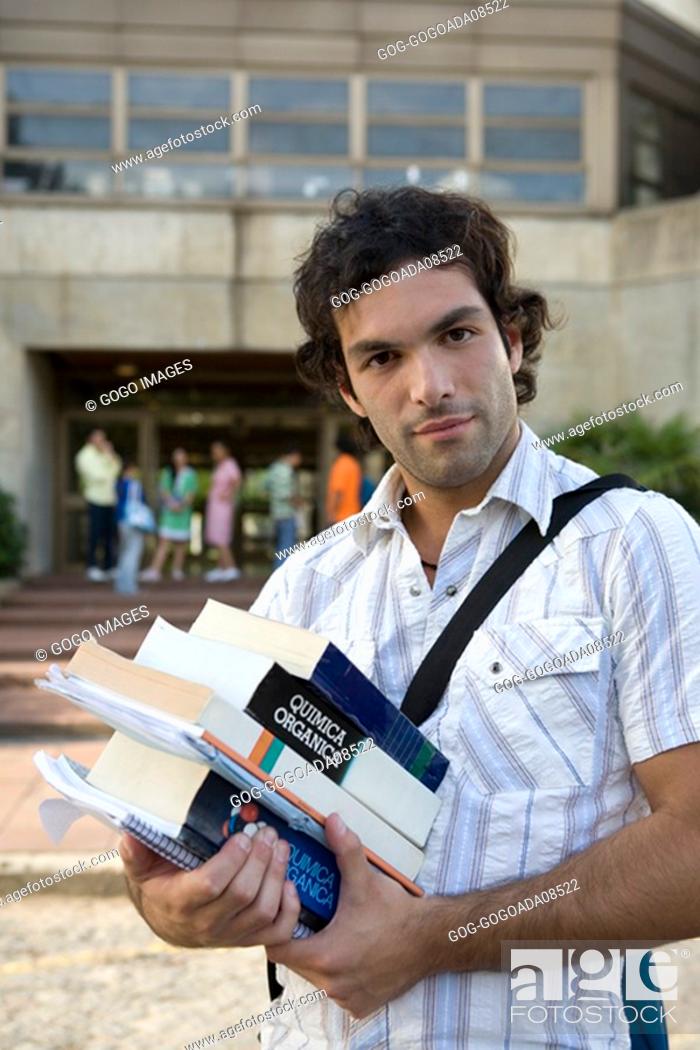 Imagen: Male student carrying stack of textbooks.