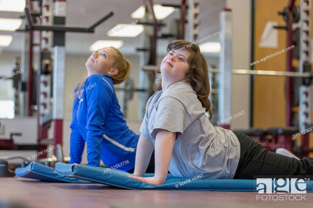 Stock Photo: Young woman with Down Syndrome working out with her trainer on a exercise mat in gym.