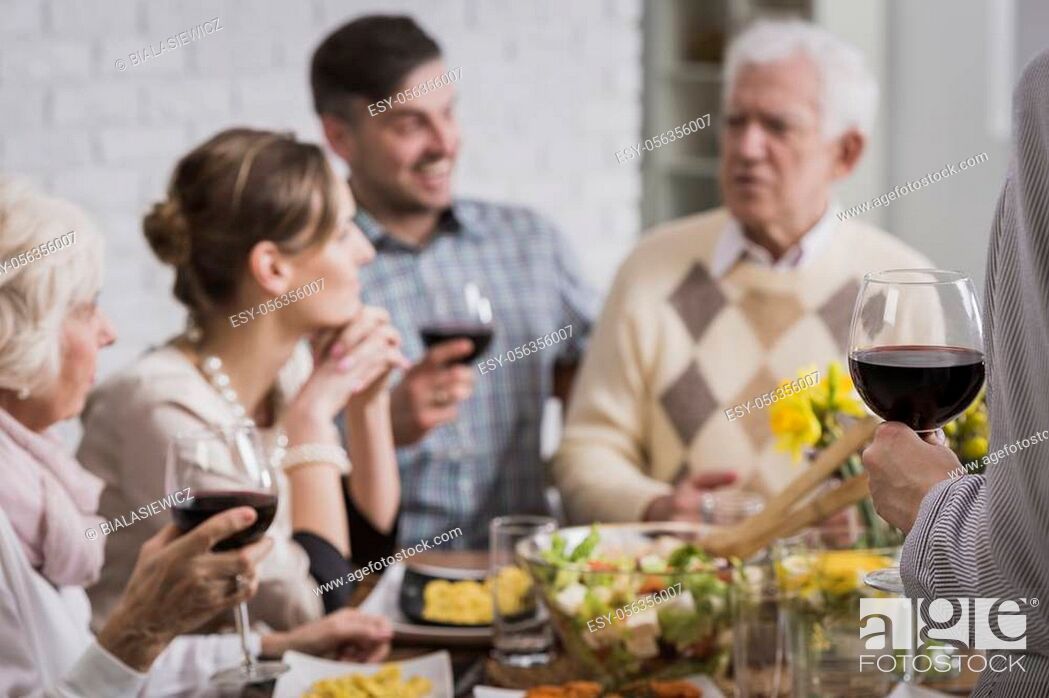 Stock Photo: Happy family sitting beside table during meal, drinking wine.