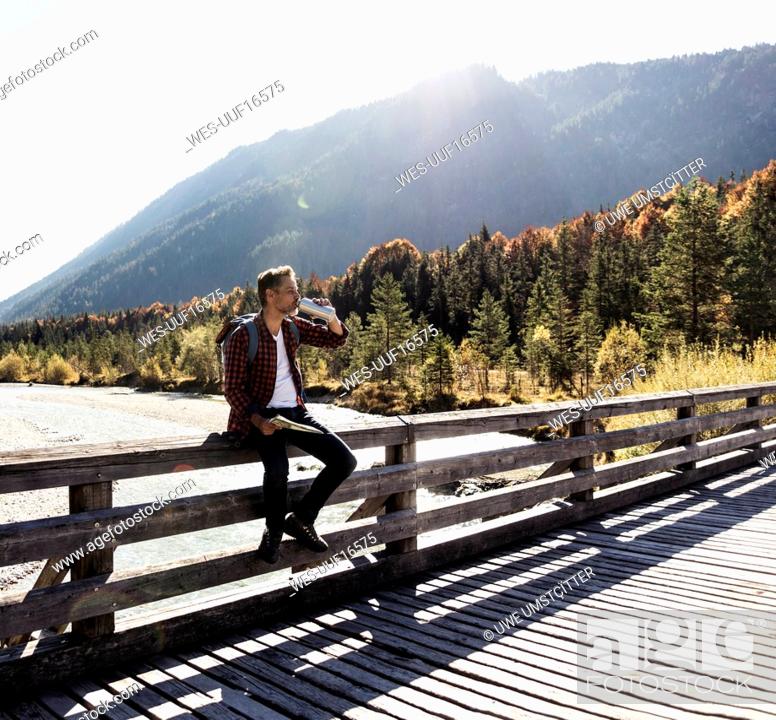 Stock Photo: Austria, Alps, man on a hiking trip having a break on a bridge.